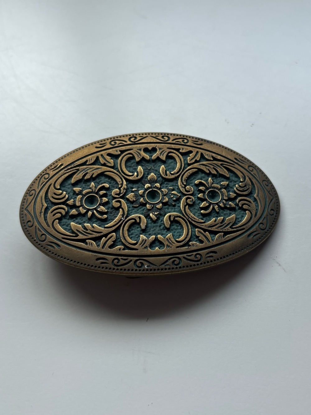 Vintage oval brass belt buckle with a vine/floral intricate design